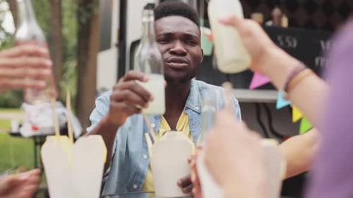 Young Man Cheers with Friends at Food Truck