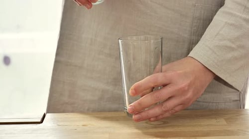 Agua. Modo de bebida. Una mujer vierte agua en un vaso, un vaso transparente
.