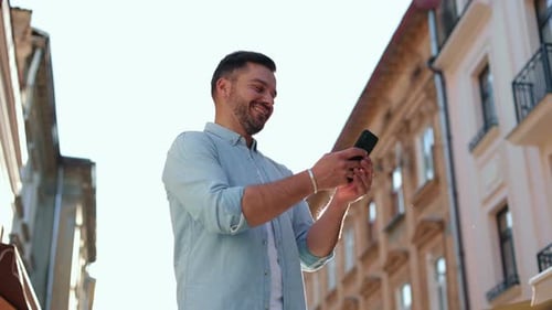 Man Using Phone on European City Street