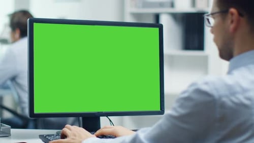 Businessman Working on a Personal Computer with Green Screen on. Colleague in the Background. Offic
