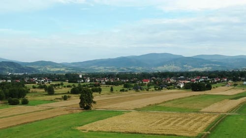 Landscape aerial view of villages and fields with mountains and blue sky in the background