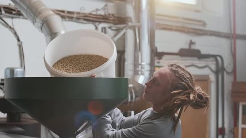 Male Technician Adding Coffee Beans to Grinding Machine at Factory