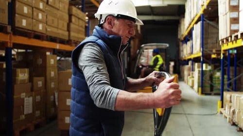 Senior Male Warehouse Worker Pulling a Pallet Truck