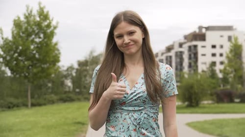 Cheerful Woman Giving Thumbs Up in City Park