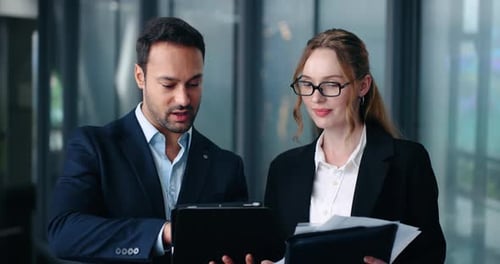 Business colleagues talking and reviewing documents in modern office hallway