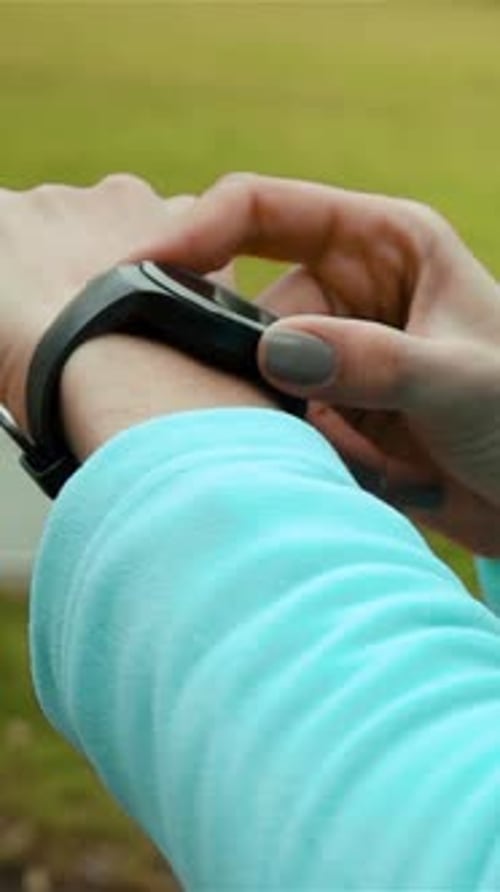 Vertical of Woman Runner Using Smart Watch Fitness Tracker in Park