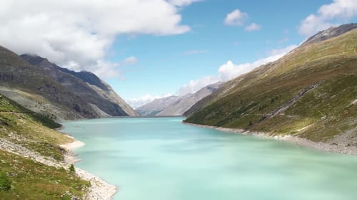 aerial flight over turquoise blue lake in the swiss alps during beautiful summer months, hiking para