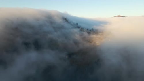 View From Above of Vibrant Landscape of Foggy Clouds Covering Mountain Hills and Village Houses at