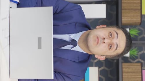 Man in Suit Talks on Laptop in Office