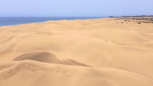 Sand dunes desert against seascape in Maspalomas Gran Canaria deserts near seashore. Aerial drone