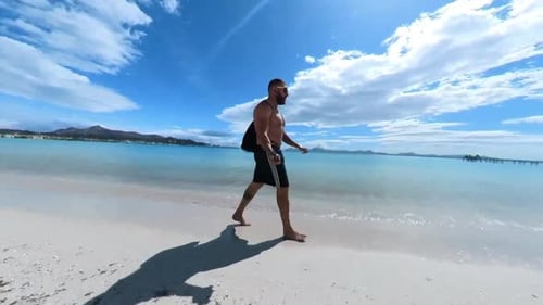 Mann spaziert am Strand von Alcudia auf Mallorca