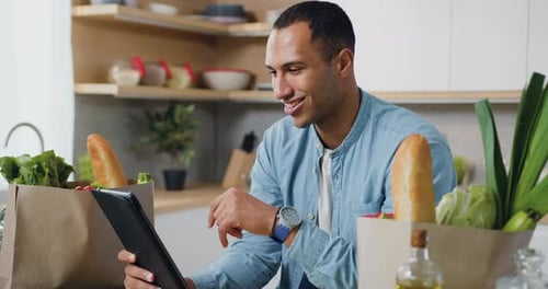 Man using electronic tablet pc in kitchen. Man searching food recipe in tablet computer. Close up