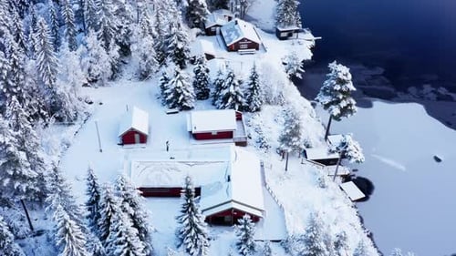 Panorama Of Small Cabins Between The Frozen Lake And Snow Covered Forest. aerial