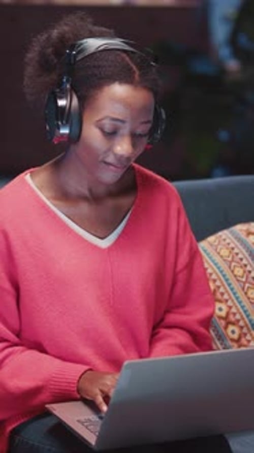 Woman Works on Laptop at Night with Headphones