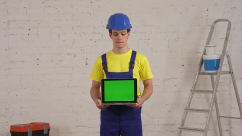Medium Video of a Young Construction Worker Standing in the Room Holding a Laptop with Advertising