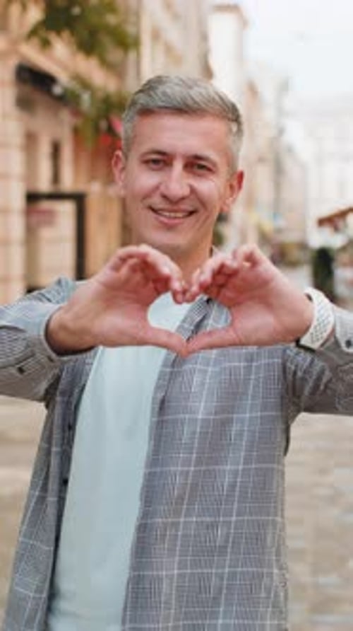 Caucasian Man Makes Symbol of Love Showing Heart Sign Express Romantic Feelings on City Street
