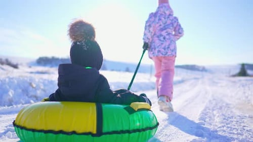 Crianças engraçadas deslizando em tubos de neve na encosta ao ar livre no inverno, trenós infantis deslizam colina abaixo