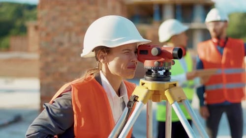 Una joven topógrafa vestida de cerca con ropa de trabajo y casco toma medidas con un casco Theodolite Stand