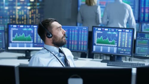 Der Börsenhändler schließt über das Headset einen Deal mit einem Großkunden ab. Er arbeitet mit anderen Brokern zusammen