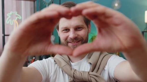 Smiling Man Makes Heart Shape with Hands