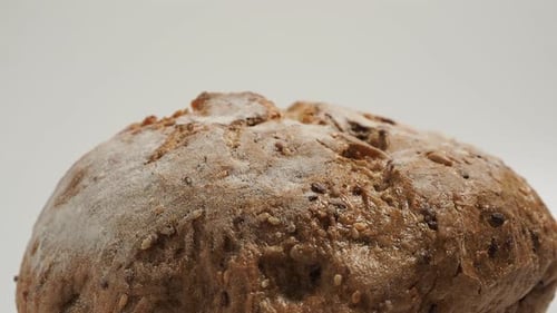 Rotation of dark bread on a white background. Round bread with grains. Close-up.