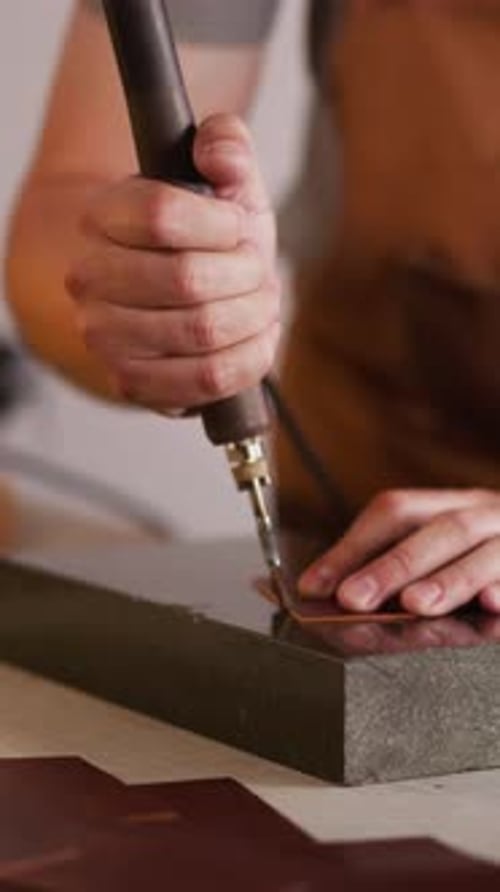 Artisan Cutting Leather at Workbench in Workplace