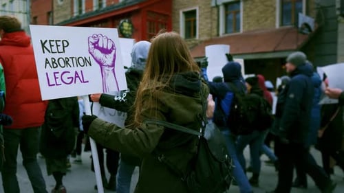 Protestors March Holding Signs in City Streets
