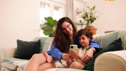 Mother and Child Using Mobile Phone on Sofa
