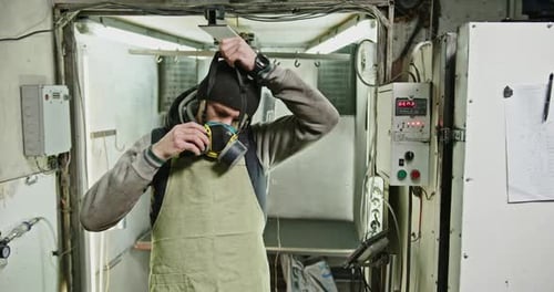 Worker Puts on Mask in Workshop, Ready to Work