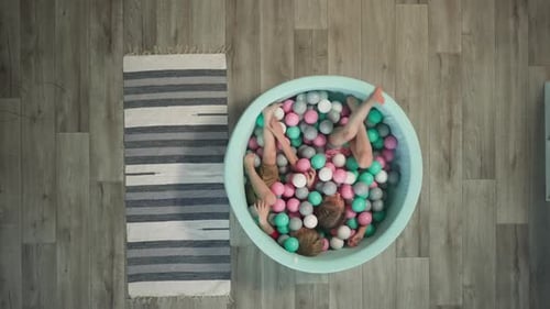 Un petit garçon et une fille d'âge préscolaire jouent allongés dans une piscine sèche
