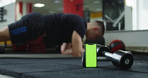A Video Featuring a Green Screen Smartphone and a Man Doing Ab Exercises in the Background