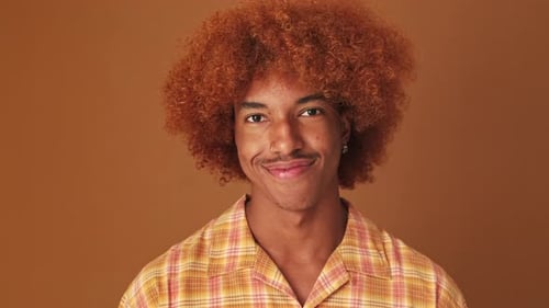 Close up, guy smiling widely looking at the camera isolated on brown background in studio
