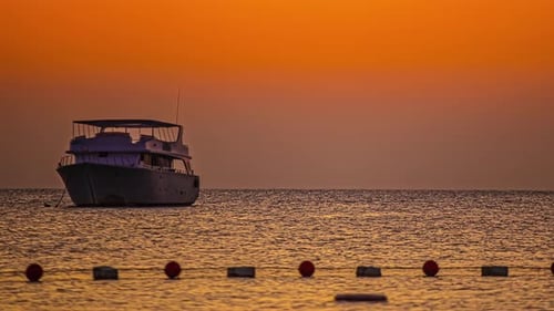Sky changing colors during sunset while a boat is moored at an anchor. Timelapse