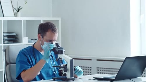 Doctor Looks at Microscope in Light Room