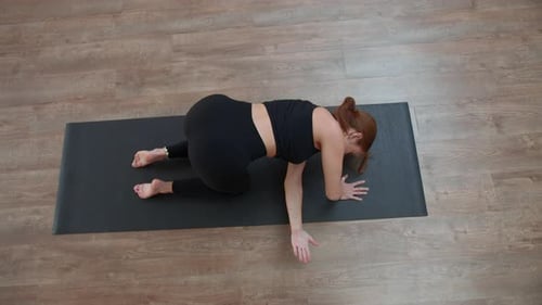 Frau in schwarzer Sportkleidung führt im Yoga-Kurs Yoga-Asanas auf der Matte durch. Medien. Gesunder Lebensstil