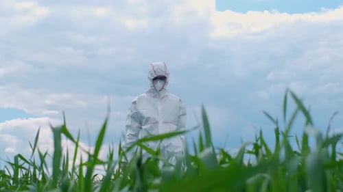 A biologist in a mask and a protective suit explores the field with the help of modern technology. T