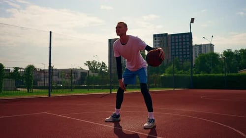 a Tall guy basketball player with the ball shows his dribbling skills during practice on the court