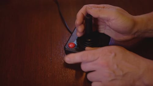 Hand Using Vintage Black Joystick on Wood Table