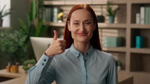 Cheerful Woman Gives a Thumbs Up in Office Setting