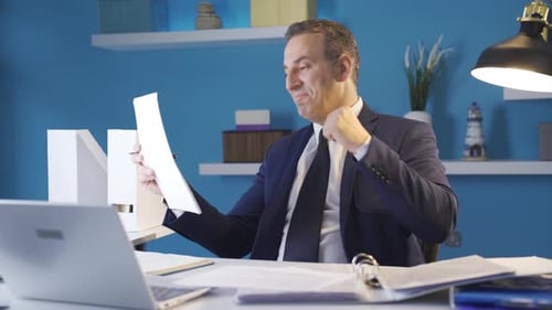 Businessman Reads Documents and Celebrates at Desk