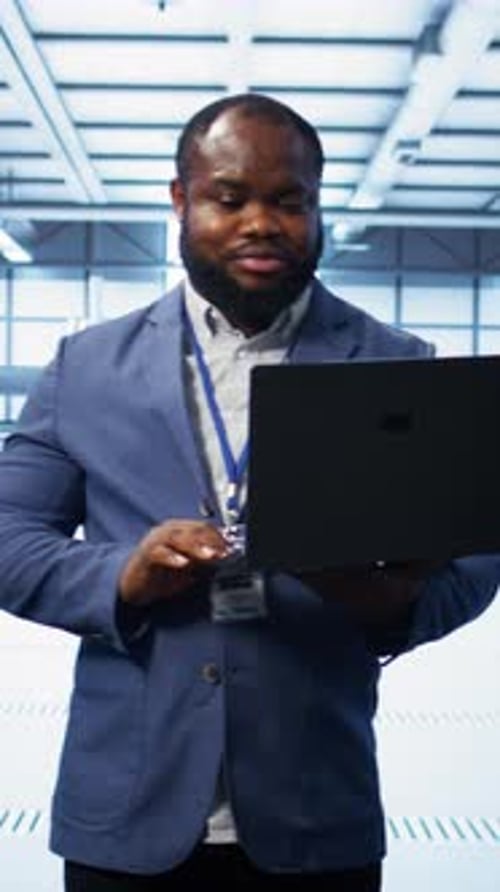 Vertical Video IT Engineer Working on Laptop in Data Center Overseeing Server Operations