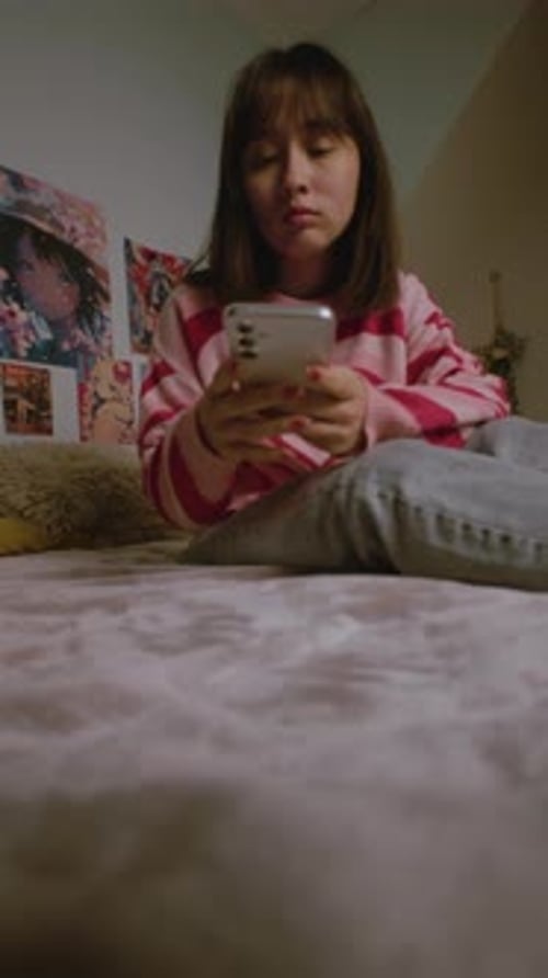 Asian Girl Uses Smartphone Then Locks Phone and Rests in Bed