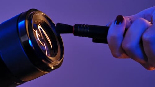 Cleaning Camera Lens with Brush Under Neon Light