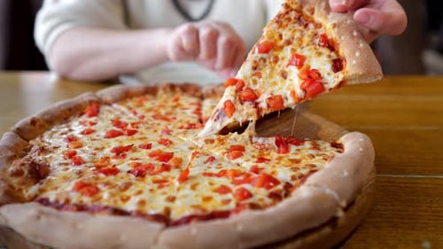 Woman Picking Up Slice of Pizza with Melted Cheese