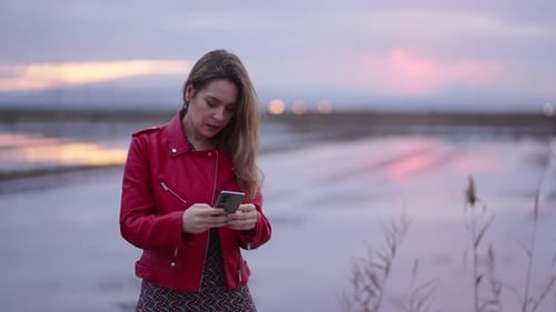 Eine Frau in einer roten Jacke nimmt sich mit ihrem Handy auf