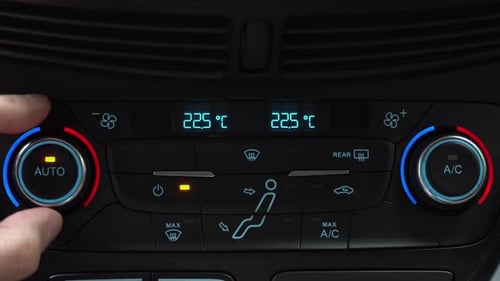 Fingers turn toggle switch of car air conditioner increasing temperature in cabin to 22 degrees