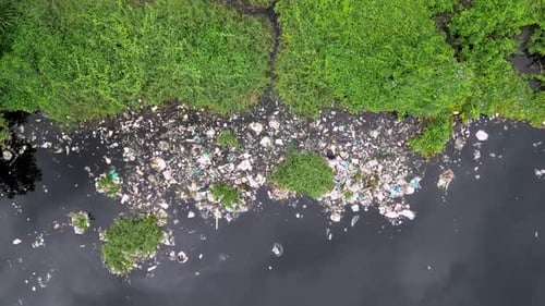 Aerial look down debris contamination alongside riverbank