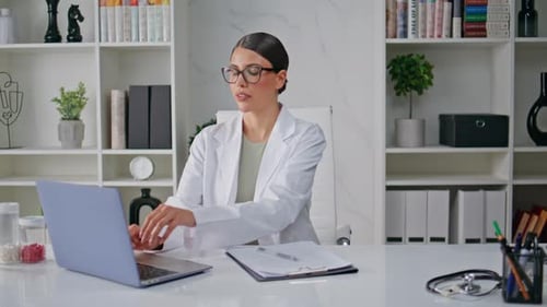 Woman Doctor Working Laptop Attentively in Modern Healthcare Clinic Closeup