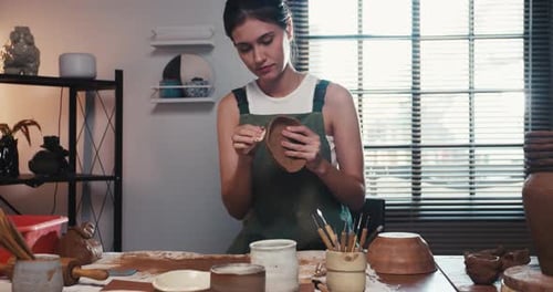 A female ceramicist is creating a new pottery in the workshop.