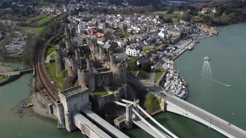 An aerial view of Conwy Castle on a sunny day, flying right to left around the castle with the town